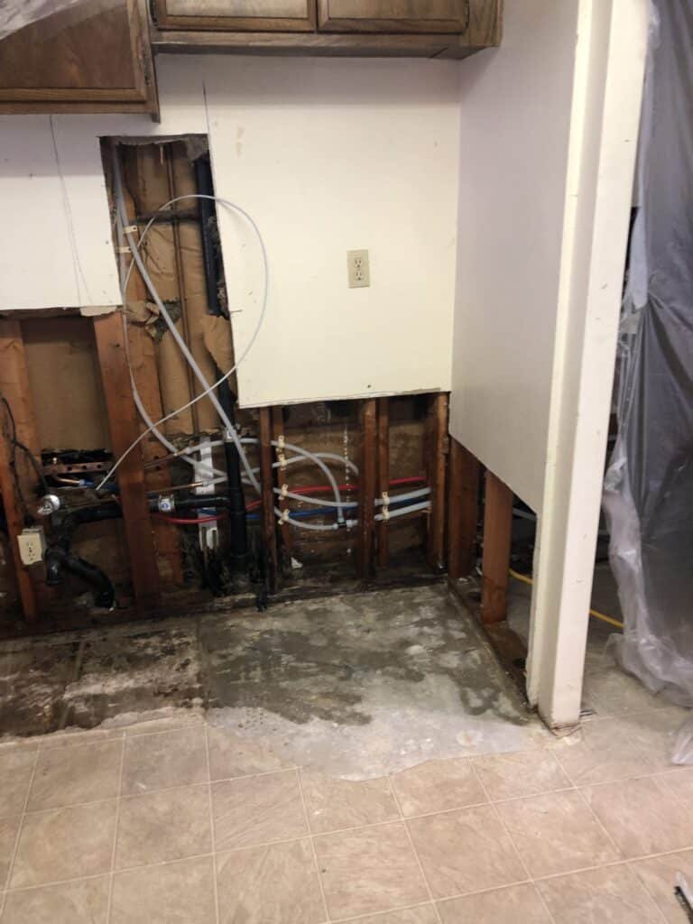 Kitchen wall and floor area opened around plumbing lines