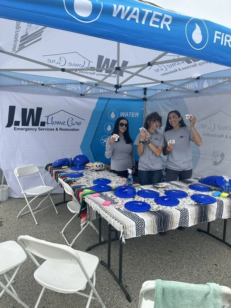JW Home Care team members under a branded canopy at an outdoor event