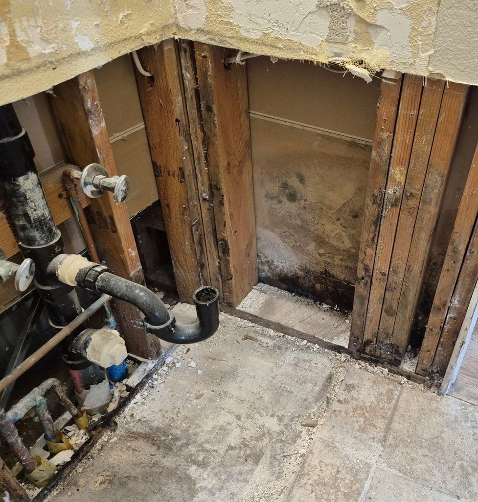 Opened wall cavity with discolored materials near laundry plumbing