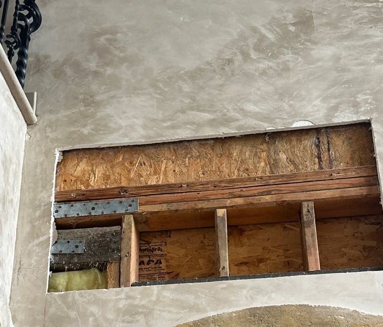 Wall covering removed to expose framing beneath a stained ceiling