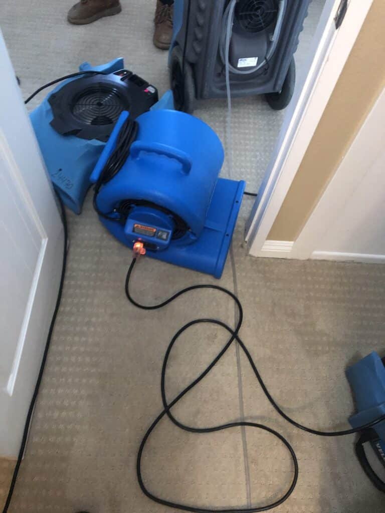 Air movers operating in a carpeted hallway near laundry equipment
