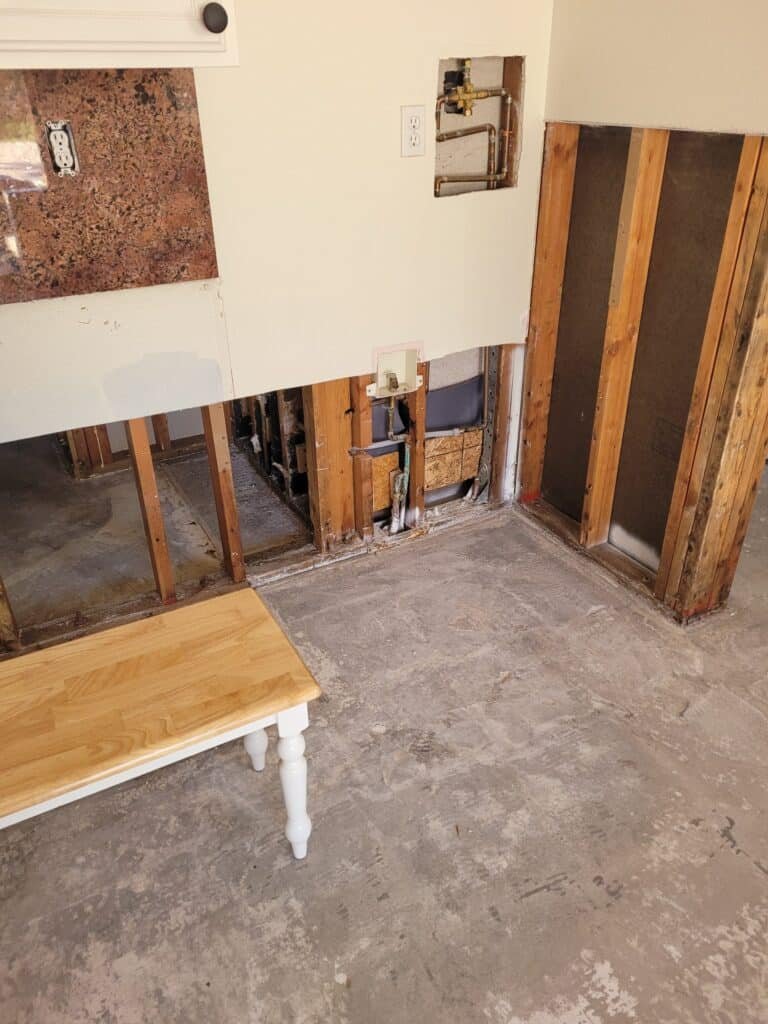 Lower wall sections opened to expose framing and plumbing