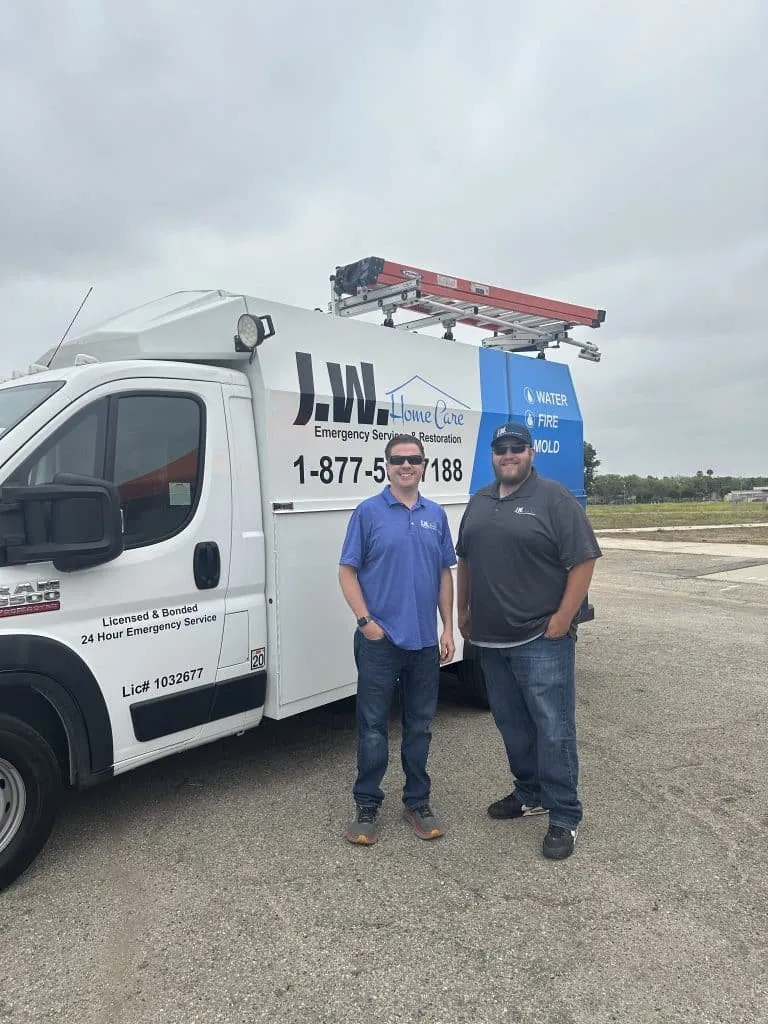 Two men standing beside a JW Home Care service van