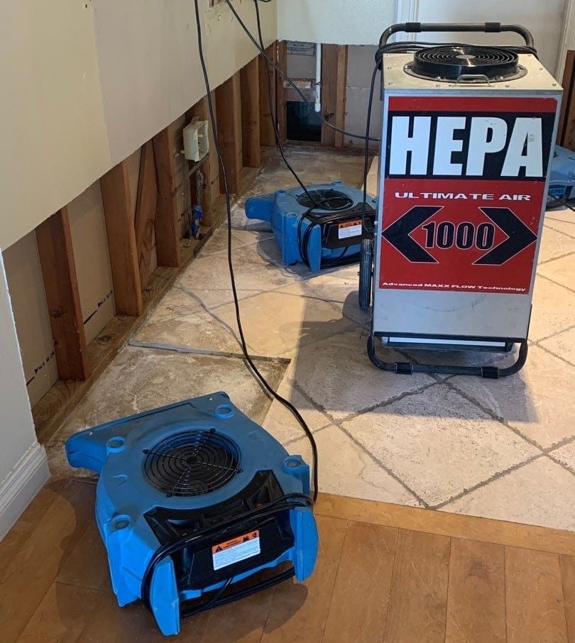 Air movers and filtration equipment beside an opened wall
