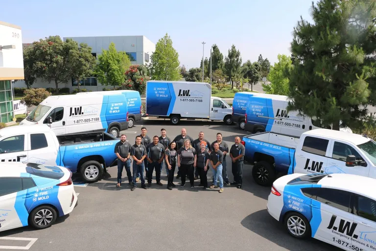 JW Home Care team standing with company service vehicles