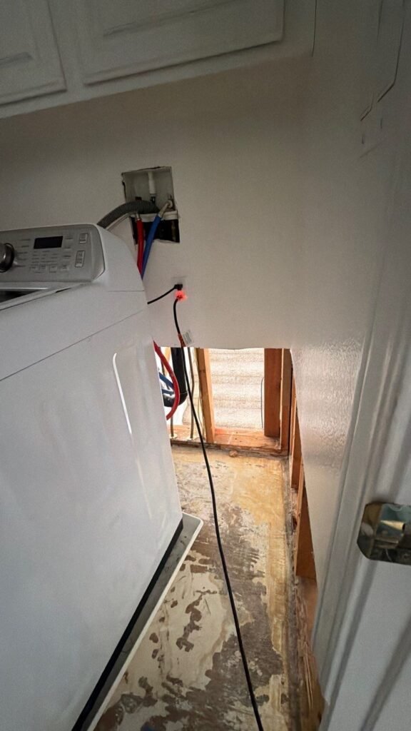 Wall materials removed beside a washing machine