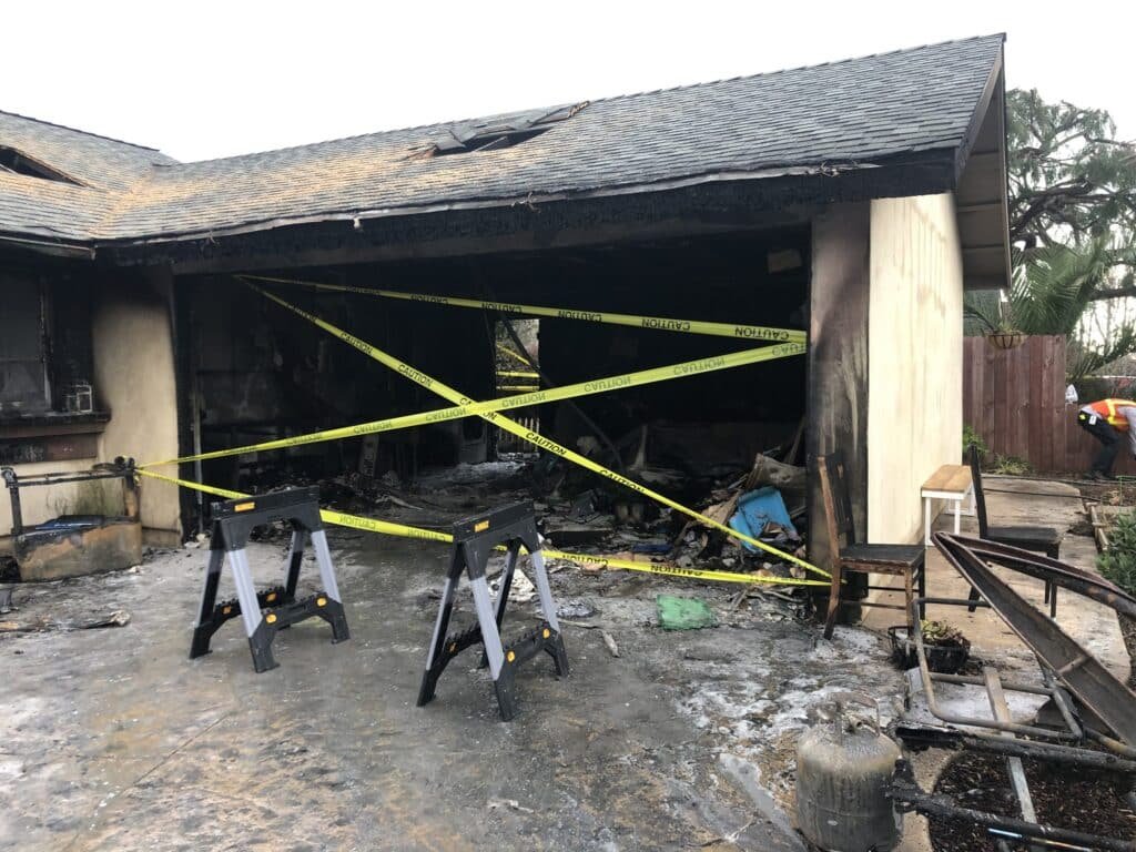 Fire-damaged house with a charred garage opening — Camarillo