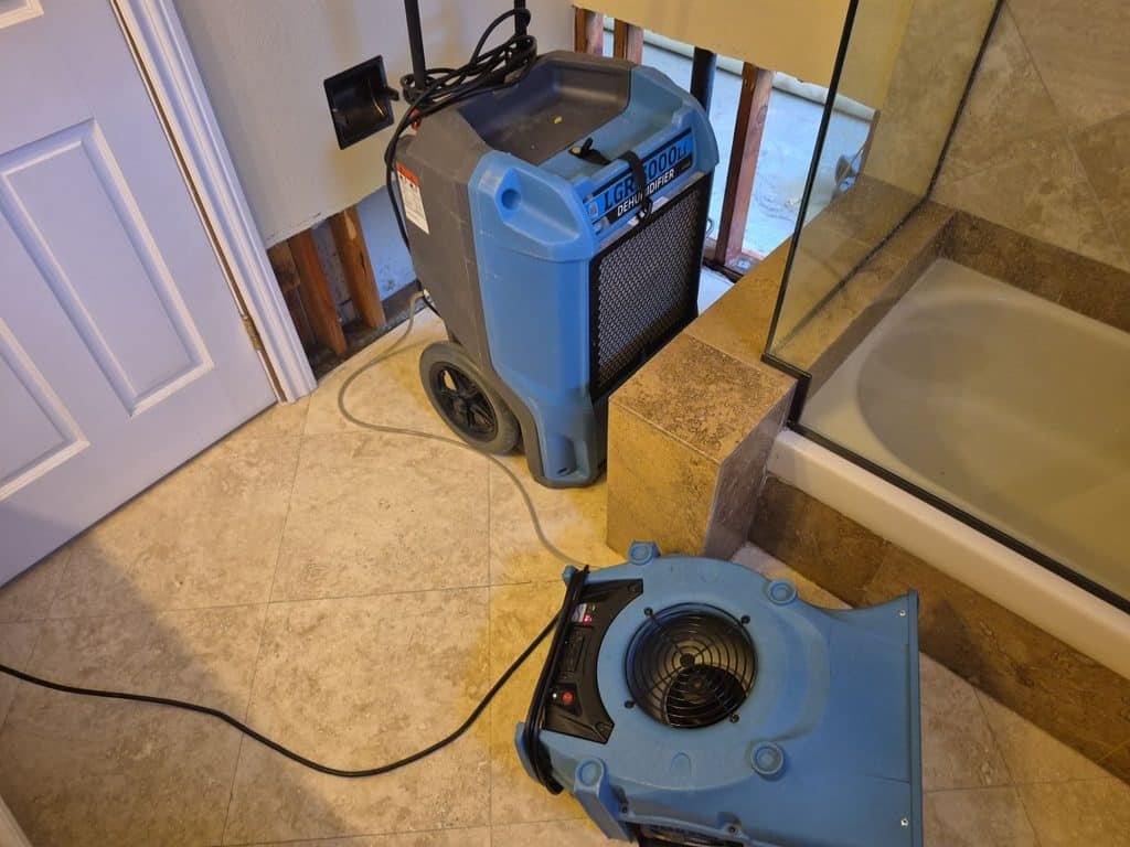 Air mover and dehumidifier beside a shower in the affected Oak Park bathroom