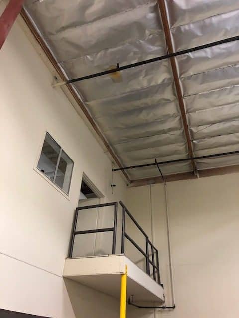 Exposed ceiling insulation in a tall interior work area