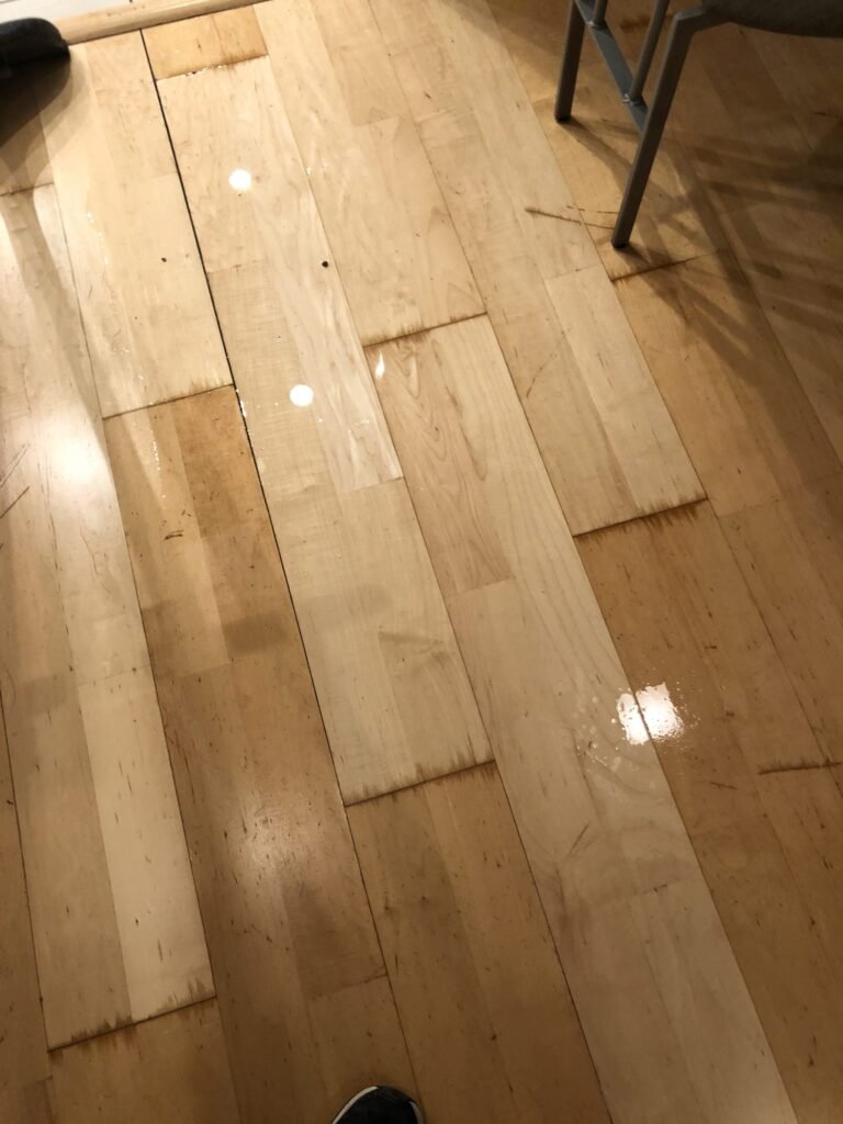 Water visible on wood flooring beside a wall