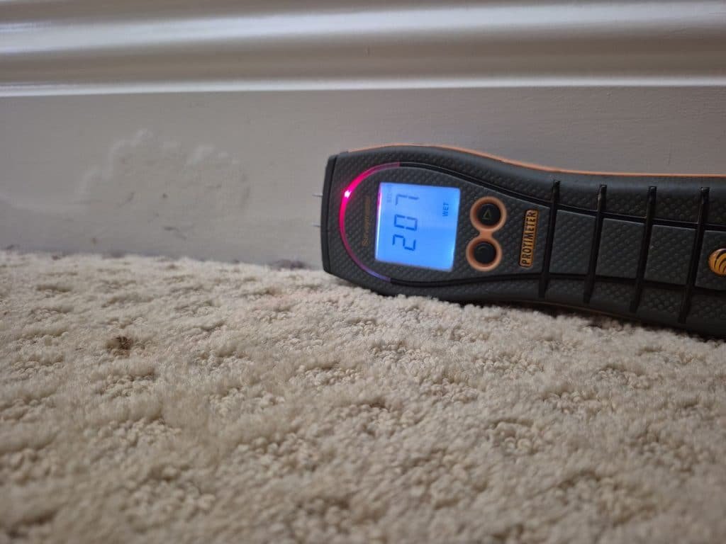 Moisture meter placed on carpet beside a baseboard during a Newbury Park slab leak project